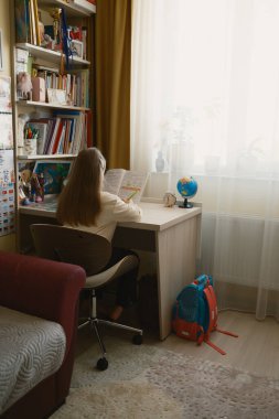 Odaklanmış öğrenci gündüzleri rahat bir evde masa başında ders çalışıyor..