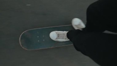 Beyaz spor ayakkabılarla, asfalt zeminde kaykay sürerken pov fotoğrafı. Çekim hareketi ve patencilerin bakış açısını vurguluyor..