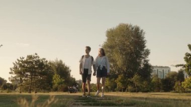 Genç bir çift el ele tutuşup parktan geçen bir patikada kameraya doğru yürüyor. Mutlular ve aşıklar..