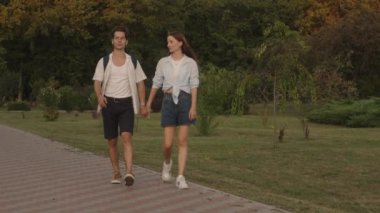 Genç bir adam ve kadın bir randevuda el ele tutuşarak parkta mutlu bir şekilde yürürler. Onlar yaz havasının ve birbirlerine eşlik etmenin tadını çıkarıyorlar..