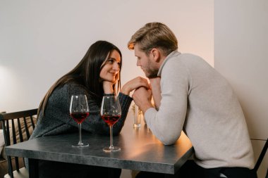 Bir çift, şarap ve mum ışığında romantik bir akşamın tadını çıkarırken aynı hassas anı paylaşıyor..