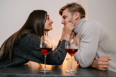 Sevgi dolu bir çift mum ışığında sıcak ve samimi atmosferi güçlendiren bir bardak şarapla romantik bir anı paylaşıyor. Romantizm, kutlama ve birliktelik temaları için ideal..