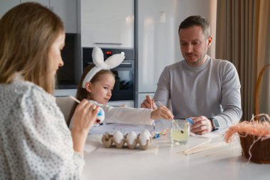 Family gathering for Easter egg decorating activity, spreading joy and festive spirit. clipart