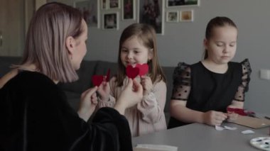 Anneler ve kızları evde sevgililer günü kartı hazırlıyorlar..