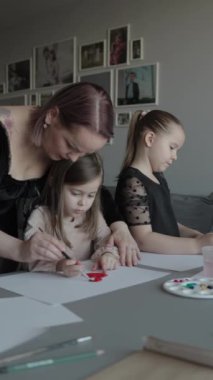 Anne ve iki kız evde birlikte resim yapıyorlar. Sıcak aile zamanı.