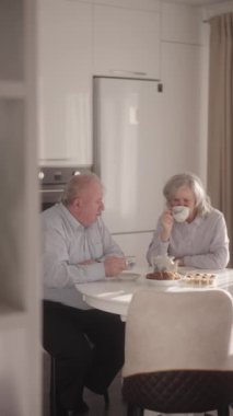 Yaşlı çift mutfaklarında çay ve pastanın tadını çıkarıyor.