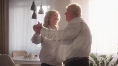 Mutlu yaşlı çift oturma odalarında dans ediyor..