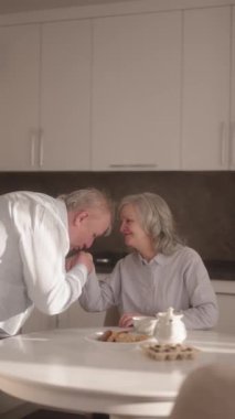 Kıdemli adam karılarının elini öpüyor ve çay ve kurabiyelerle birlikte eğleniyorlar..