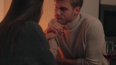 Mum ışığında el ele tutuşan ve birbirine bakan romantik çift.