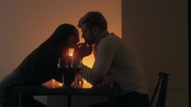 Romantik çift, mum ışığında şarap eşliğinde özel yemeğin tadını çıkarıyor.