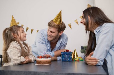 Mutlu bir aile, doğum gününü pasta, hediyeler ve kahkahalarla kutluyor.