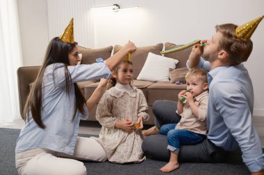 Neşeli bir aile evde parti şapkaları ve aksesuarlarıyla çocukların kutlamalarından hoşlanır..