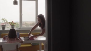 Bir anne ve iki kızı mutfaklarında çikolatalı pasta yapıyorlar. Gülüyorlar, gülüyorlar ve eğleniyorlar.