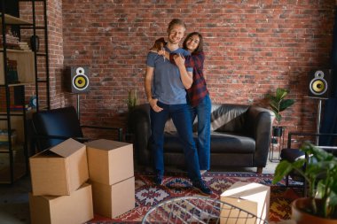 Neşeli bir çift yeni evlerinin tadını çıkarıyor. Etrafı boş kutular ve rahat mobilyalarla çevrili..