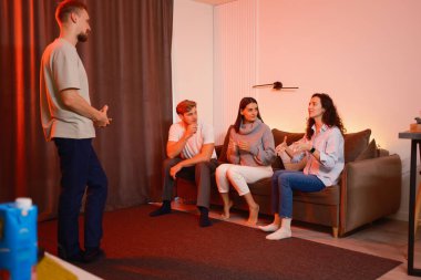 Dört arkadaş sıcak aydınlatılmış bir oturma odasında gevşek bir sohbetin tadını çıkarıyor.