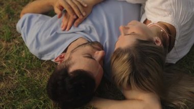 Çiftler çimenlerde dinleniyor, yaz günbatımının tadını çıkarıyorlar..