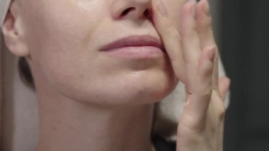 Yüzüne nemlendirici sürerken, cildine sağlıklı ve ışıl ışıl cilt için odaklanan bir kadının yakın çekimi..