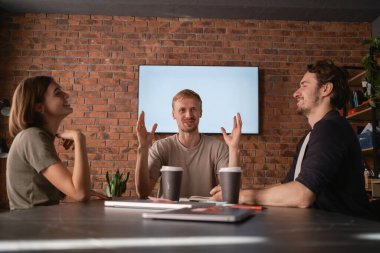 Bir grup meslektaş, rahat ve gayri resmi bir ofis ortamında tartışmanın keyfini çıkarıyorlar.