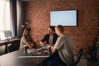 Üç profesyonelden oluşan bir ekip yaratıcı bir ofiste iş fikirlerini tartışıyor..