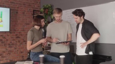 Üç meslektaşı ofislerinde tablet kullanarak bir projeyi tartışıyor..