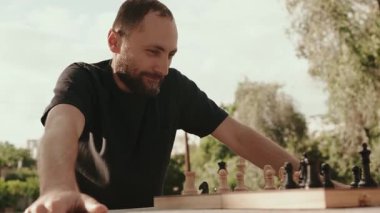 Bir adam parkta satranç oynarken bir sonraki hamlesini düşünür. Kamera onun stratejik düşüncelerine ve oyunun yoğunluğuna odaklanıyor..