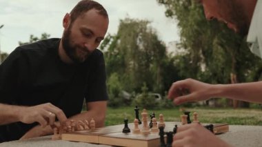İki erkek arkadaş bütün gün parkta piknik masasında oturup satranç oynamaya odaklanmışlar..