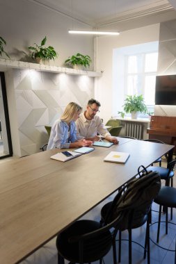 Bitkiler, teknoloji ve işbirliği ile modern ofis ortamında profesyonel takım çalışması