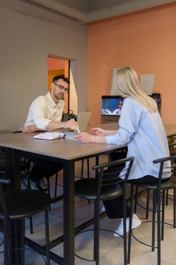 Şık bir ofis ortamında profesyonel bir tartışmaya giren iki kişi.