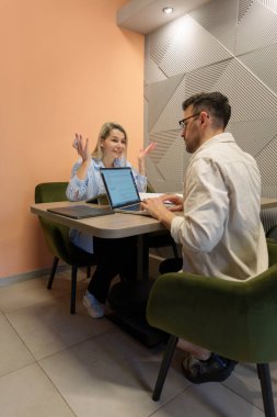 Çağdaş bir ofis ortamında çalışırken iki meslektaş sohbet eder..