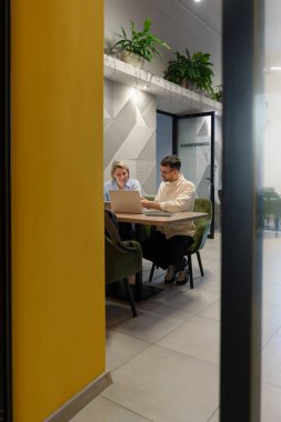 Yeşillik ve canlı renklere sahip modern bir çalışma alanında profesyonel takım çalışması.