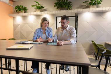 Tabletle ve açık notlarla bir masada iş tartışan iki profesyonel..