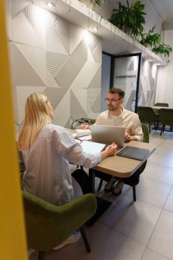 Çağdaş bir ofiste, geometri ve yeşillik dekoru artırıcı odaklı iki kişi işbirliği yapar..