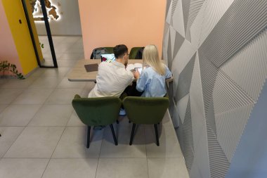 İki kişi modern, yapılandırılmış bir odada otururken bir projeye odaklandılar..