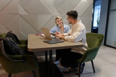 Ekip üyeleri ortak bir çalışma alanında dizüstü bilgisayar ve notlar kullanarak fikirleri tartışıyor