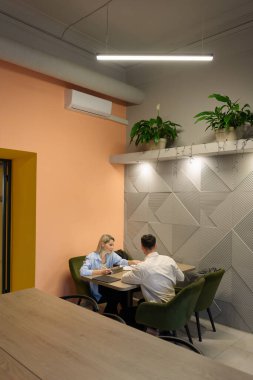 Çağdaş bir çalışma alanında otururken proje detaylarını tartışan ekip üyeleri.