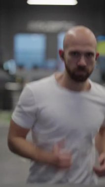 Spor salonundaki koşu bandında koşmaya kararlı adam fitness hedeflerine odaklanmış..