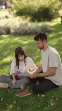 Şefkatli bir baba park ortamında kızına ödevlerinde yardım eder. Bu sahnede aile bağları ve öğrenme vurgulanıyor..