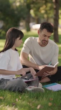 İlgili bir baba okul kızına parkta çalışmasında yardım eder. Eğitimini ve aile zamanını gösterir. Aile, eğitim ve ebeveynlik konuları için mükemmel.