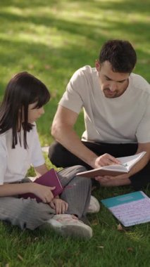 Şefkatli bir baba kızına açık havada okul ödevlerinde rehberlik eder, öğrenme ve aile bağı kurma sevgisini teşvik eder..