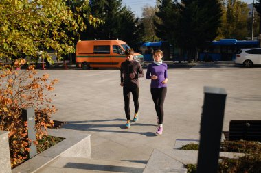 Güneşli bir günde, bir karı koca şehir ortamında birlikte koşuyorlar.
