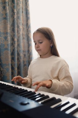 Genç bir kız rahat, iyi ışıklandırılmış bir odada elektronik klavye çalıyor. Sahne, müzik becerilerini bilemeye çalışırken onun odaklanma ve adanmışlığını yakalıyor..