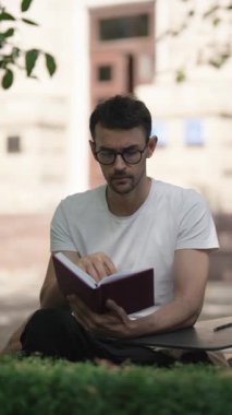 Parkta kitap okuyan bir adam. Kitap okuyan dalgın bir adam. Öğrenci not defterinden notlar okuyor..