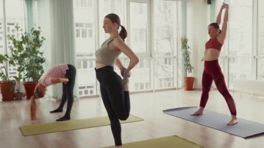 Yoga sınıfı: Parlak bir stüdyoda esneme hareketleri yapan kadınlar.