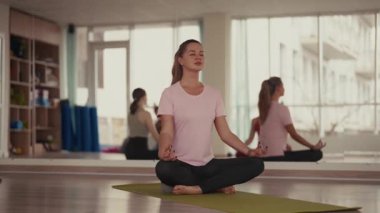 Yoga dersinde meditasyon yapan genç bir kadın. Huzurlu bir düşünceyle gözleri kapalı..