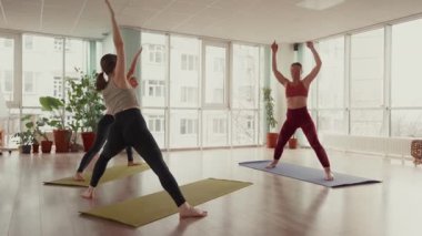 Parlak bir stüdyoda yoga dersinden zevk alan kadınlar..