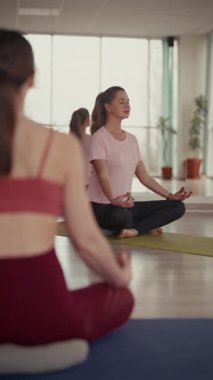 Nilüfer çiçeği pozunda meditasyon yapan kadınlar, spor salonundaki yoga dersinde..