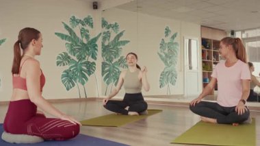 Üç kadın bir fitness merkezinde birlikte yoga yapıyor..