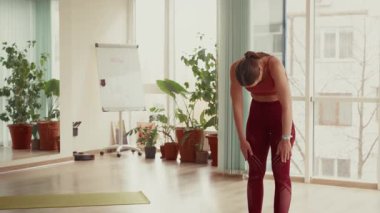 Parlak bir odada yoga egzersizleri yapan genç bir kadın..