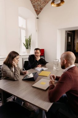 Bir grup profesyonel şık bir ofiste beyin fırtınası yapıyor ve fikirleri paylaşıyorlar.