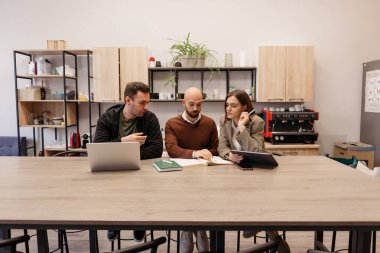 Kaynakları olan ortak bir ofis ortamında fikir alışverişinde bulunan üç meslektaşımız.